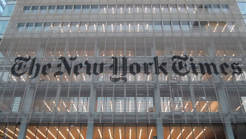 The New York Times logo displayed on the exterior of a modern office building facade.