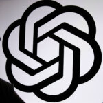 Silhouette of a person holding a phone in front of a large OpenAI logo on a white background.