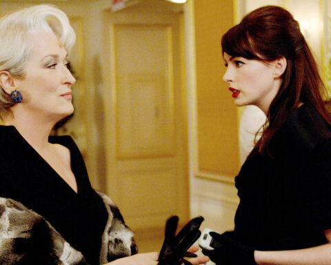 Meryl Streep and Anne Hathaway in a scene from The Devil Wears Prada, dressed in black with a fur coat and gloves.