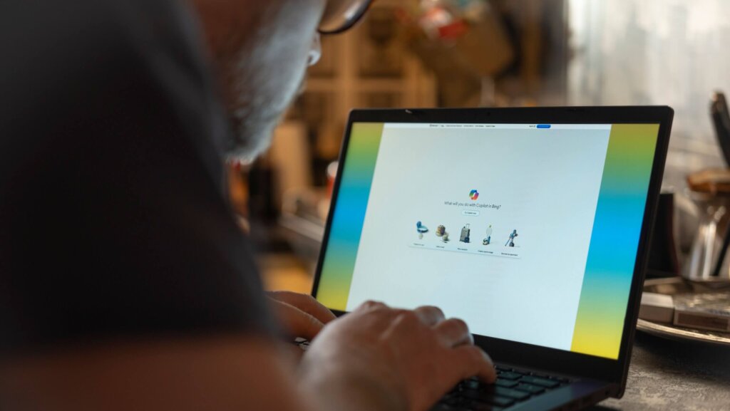 Person using a laptop displaying the Bing Copilot feature with options like travel plan and create a painting