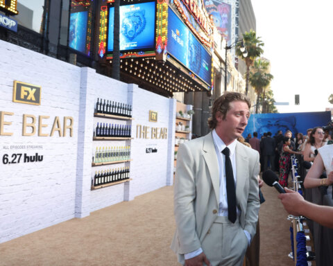 Actor Jeremy Allen White in a light suit being interviewed at FX The Bear premiere event on a beige carpet.
