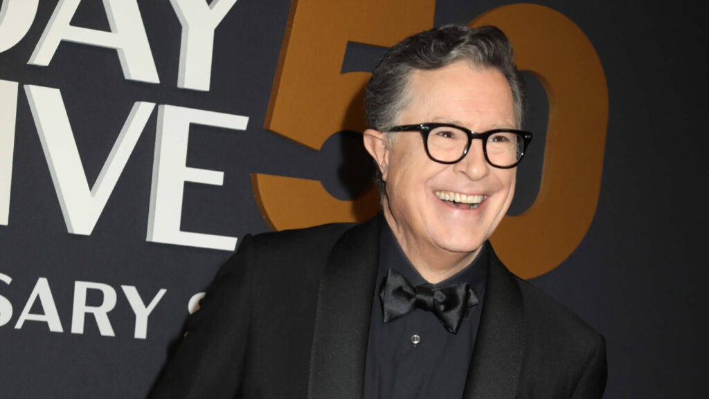 Stephen Colbert smiling in a black tuxedo at the 50th anniversary of Saturday Night Live event