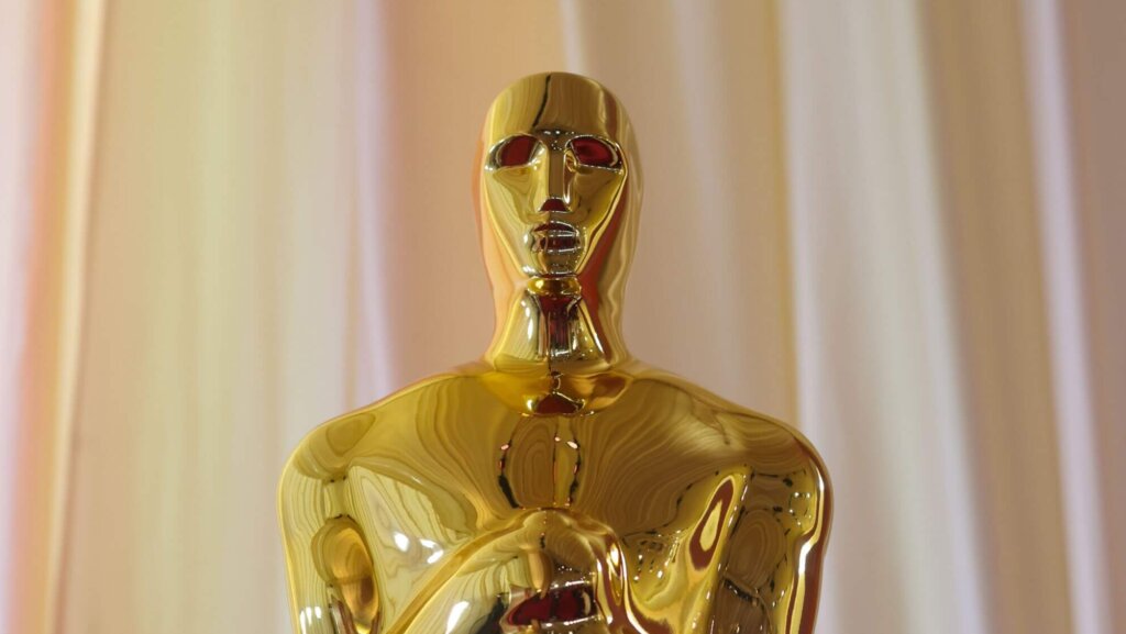 Close-up of a gold Oscar statuette against a beige curtain background