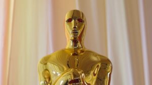 Close-up of a gold Oscar statuette against a beige curtain background