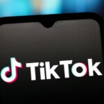 TikTok logo displayed on a smartphone screen with a blurred colorful background