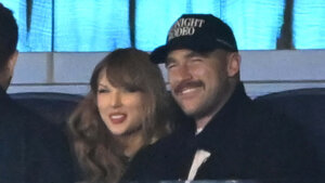 Taylor Swift and a man wearing a "Midnight Rodeo" cap smiling together indoors