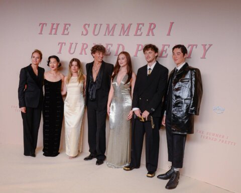 Cast members of The Summer I Turned Pretty posing at a premiere event with a branded backdrop.