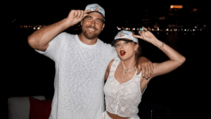 A man and woman wearing "Captain" and "First Mate" hats pose smiling at night by the water.