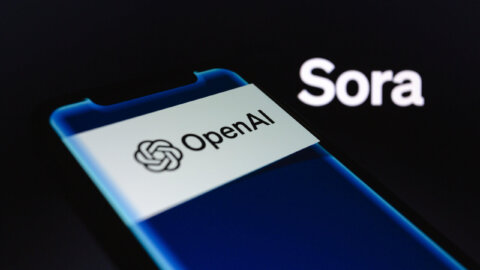 OpenAI logo displayed on a smartphone screen with the word "Sora" in the background.