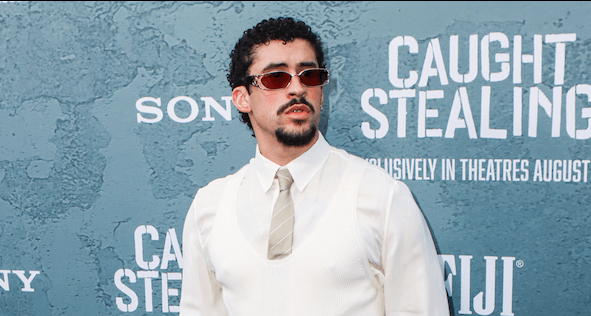 Man wearing sunglasses, white shirt, and beige tie at the "Caught Stealing" movie premiere.
