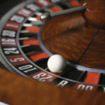 Roulette wheel with ball landing on number 23 red slot.