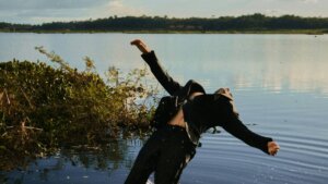 Person in black suit falling backward into a lake, splashing water around them.