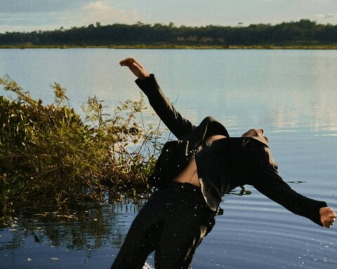 Person in black suit falling backward into a lake, splashing water around them.