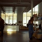 People browsing books in a modern bookstore with large windows and natural light.