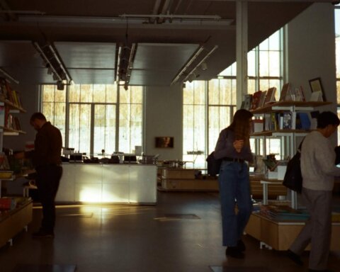 People browsing books in a modern bookstore with large windows and natural light.