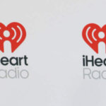 Man wearing sunglasses, a Godspeed Statue of Liberty graphic t-shirt, jeans, and white sneakers on an iHeartRadio red carpet