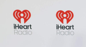 Man wearing sunglasses, a Godspeed Statue of Liberty graphic t-shirt, jeans, and white sneakers on an iHeartRadio red carpet