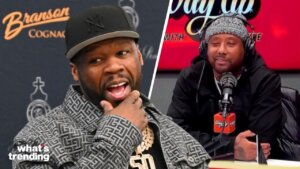 50 Cent wearing a patterned jacket and black Yankees cap, with a man in a beanie and headphones speaking into a microphone on a radio show.