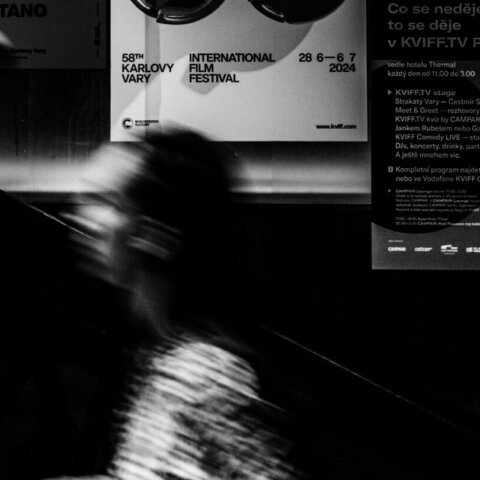 Blurred people on escalator next to posters for the 58th Karlovy Vary International Film Festival 2024