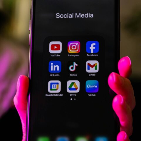 Smartphone screen displaying social media apps including YouTube, Instagram, Facebook, LinkedIn, TikTok, Gmail, Google Calendar, Drive, and Canva.