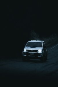 Silver Toyota Hilux driving on a dark road at night with headlights on