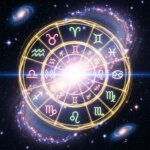 Glowing zodiac wheel with astrological symbols over a starry galaxy background with spiral galaxies.