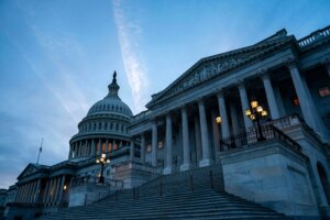 United States Capitol building at dusk with illuminated windows and street lamps