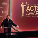 Man speaking at podium during the 32nd Annual Actor Awards presented by SAG-AFTRA with Netflix branding visible