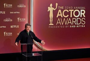 Man speaking at podium during the 32nd Annual Actor Awards presented by SAG-AFTRA with Netflix branding visible