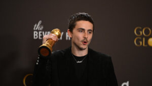 Timothée Chalamet holding a Golden Globe award at the Beverly Hilton event backdrop