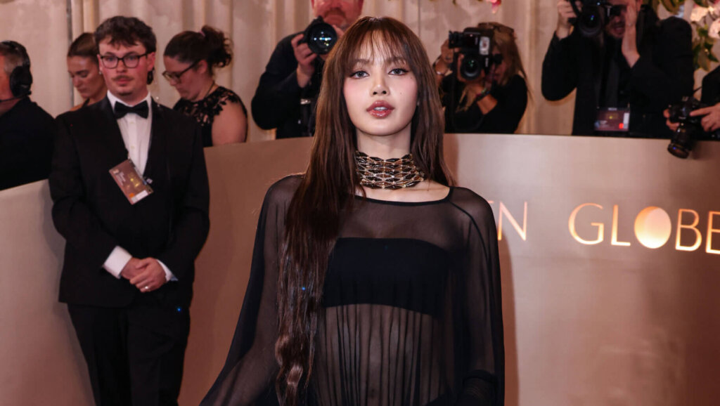 Lisa of BLACKPINK wearing a sheer black gown with a gold choker on the red carpet at the Golden Globes