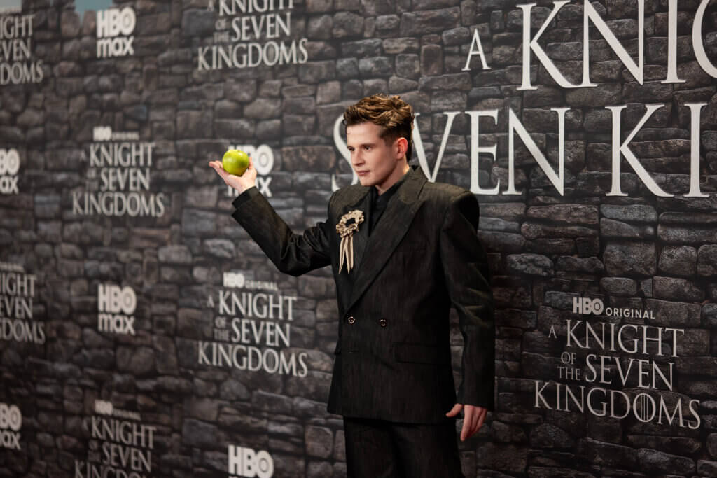 Actor Tom Glynn-Carney holding a green apple at the HBO premiere of A Knight of the Seven Kingdoms.