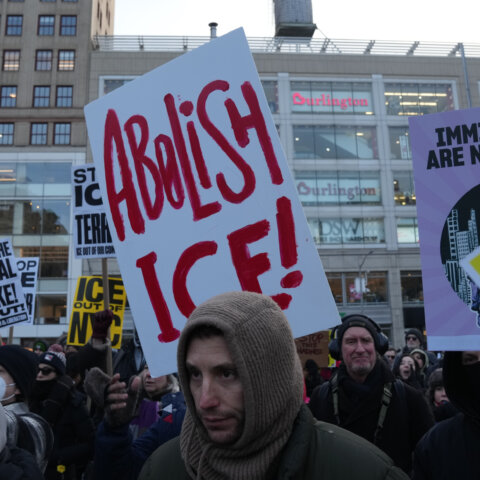 Protesters holding signs including "Abolish ICE!" and "Immigrants Are New York!" in an urban setting.