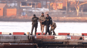 Venezuelan President Nicolás Maduro escorted by DEA agents on a dock near water.