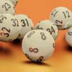 White lottery balls with black numbers scattered on an orange surface