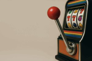 Close-up of a vintage slot machine lever with three red sevens on the reels and colorful stripes on the machine.