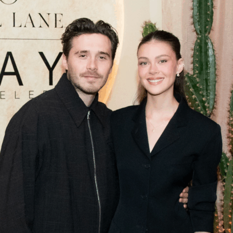 A man and woman posing together in front of a Neil Lane and Kay Jewelers sign with cacti in the background.