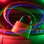 Padlock on laptop keyboard with colorful light trails symbolizing cybersecurity and data protection.