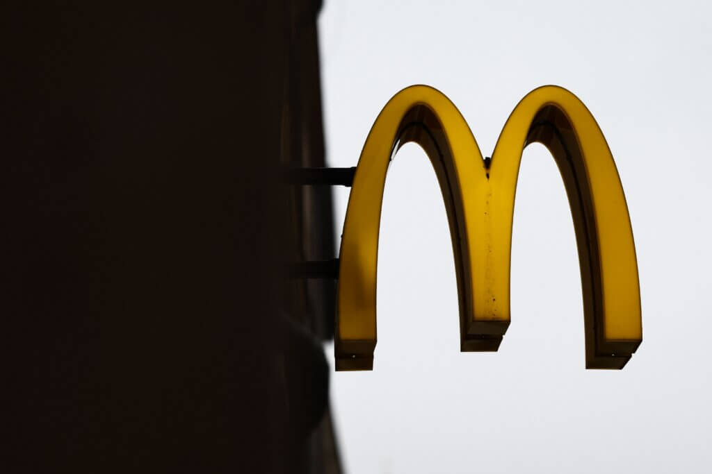 Yellow McDonald's golden arches logo sign against a gray sky background