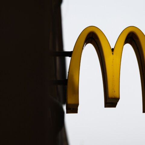 Yellow McDonald's golden arches logo sign against a gray sky background