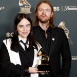 Billie Eilish and Finneas O'Connell holding a Grammy Award at a Paramount+ and CBS event backdrop