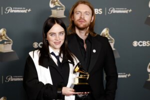 Billie Eilish and Finneas O'Connell holding a Grammy Award at a Paramount+ and CBS event backdrop