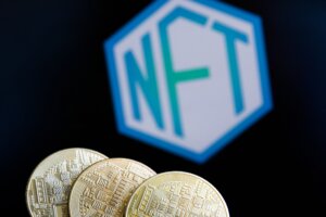 Three gold cryptocurrency coins in front of a blurred hexagonal NFT logo on a black background