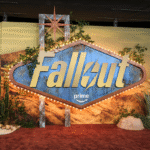 Fallout Prime promotional display with desert-themed backdrop and cacti on a red carpet.