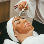 Woman receiving a brown facial mask applied with a brush at a spa or skincare treatment session