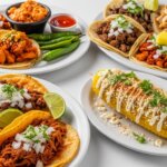 Plates of assorted Mexican tacos with lime wedges, green chilies, sauces, and Mexican street corn with mayo and cheese.