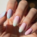 Hand with long almond-shaped nails painted in pastel gradient shades of pink, blue, and white.
