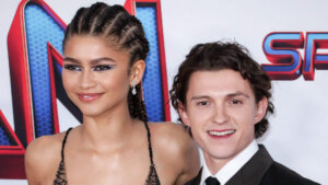 Zendaya in a spiderweb-patterned dress and Tom Holland in a black suit at a Spider-Man event.