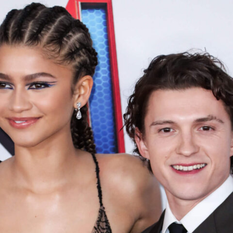 Zendaya in a spiderweb-patterned dress and Tom Holland in a black suit at a Spider-Man event.