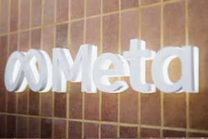 White 3D Meta logo mounted on a brown tiled wall with yellow grout lines